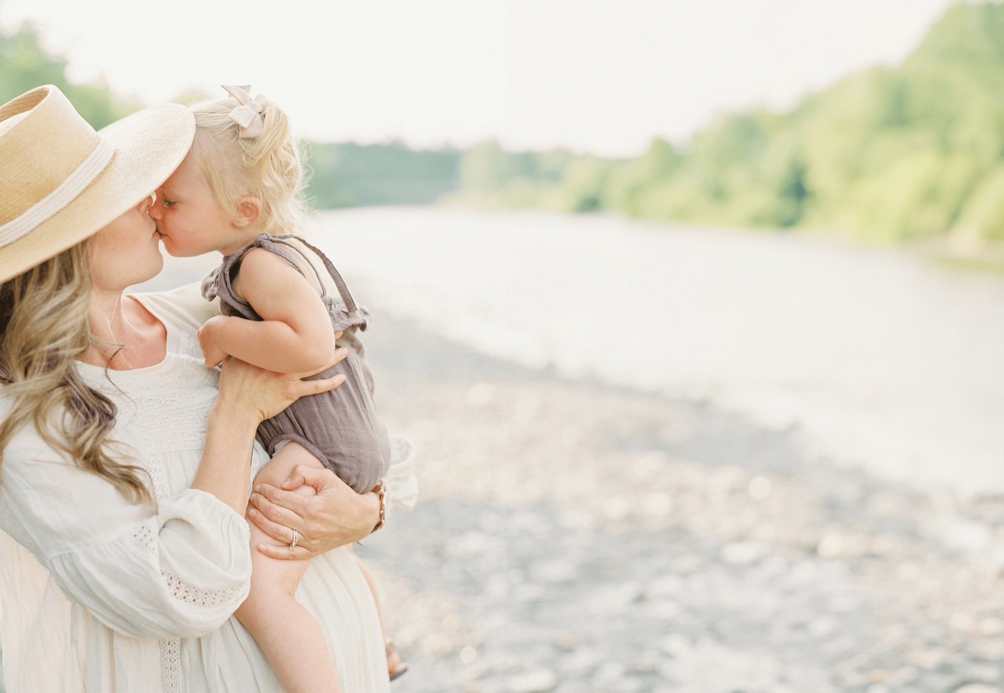 A parent holding a young child outdoors near a river